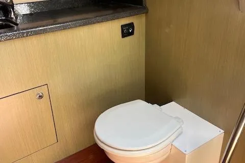 Slide: The Image of 2024 Bracewell 25 boat interior bathroom with compact toilet and wooden paneling. - 8