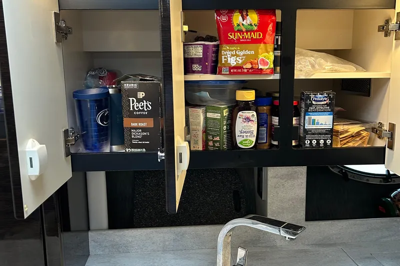 Slide: The Image of Kitchen cabinet in a 2016 Formula 40 Cruiser with assorted food items and beverages. - 42