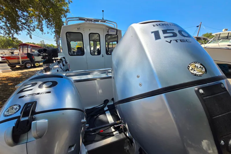 Slide: The Image of 2021 Raider 210.Explorer boat with Honda VTEC outboard engines, parked outdoors. - 4