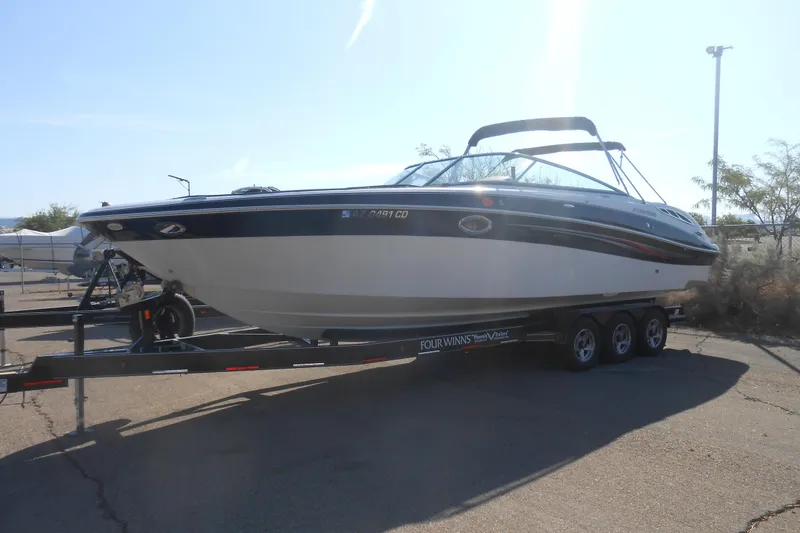 The Image of 2008 Four Winns H Series H310 boat on a trailer in a parking lot. - 0