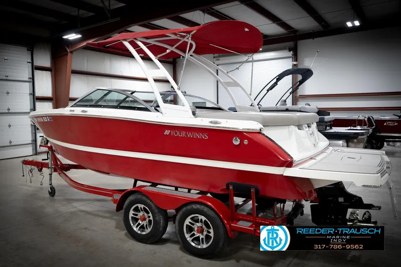 Slide: The Image of 2020 Four Winns H210 boat in a showroom, red and white design, on a trailer. - 9