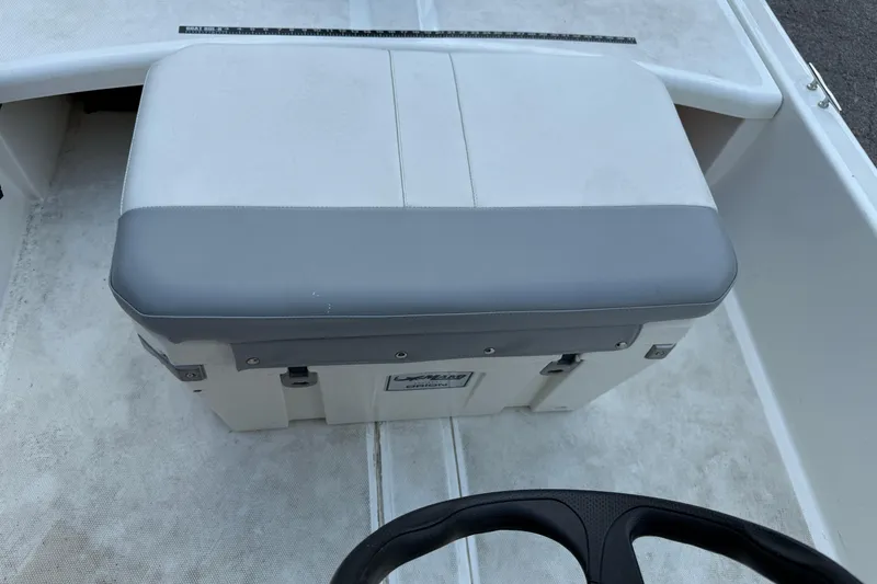 Slide: The Image of 2022 Mako Pro Skiff 15 CC boat interior with cushioned seat and steering wheel. - 9