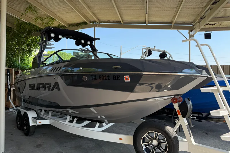 The Image of 2019 Supra SE 550 boat on trailer under canopy, sleek design, gray color. - 1