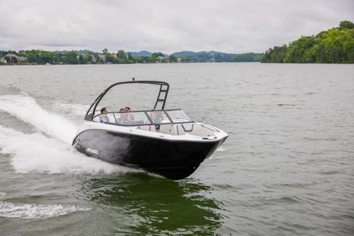 The Image of 2026 Yamaha Boats AR250 cruising on a scenic lake with lush green shoreline. - 0