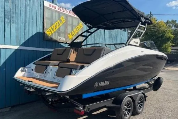 Slide: The Image of 2026 Yamaha Boats 252SD on trailer, sleek design, black and white exterior, parked outdoors. - 2