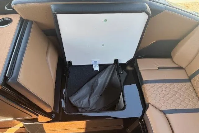 Slide: The Image of 2026 Yamaha Boats 255XD interior storage compartment with tan seating and black accents. - 25