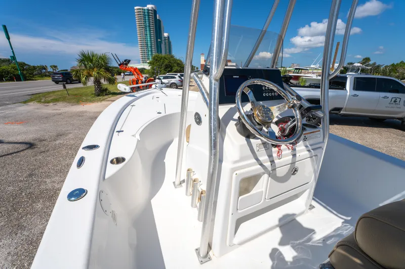 Slide: The Image of 2016 Sportsman Masters 207 Bay Boat interior with steering wheel, parked near palm trees. - 17