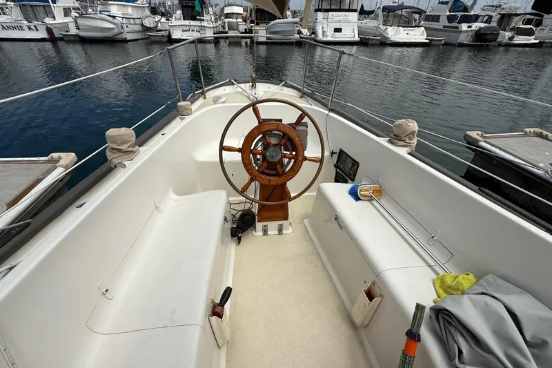 Slide: The Image of 1957 Rhodes Bounty sailboat cockpit with wooden wheel, docked at marina. - 11