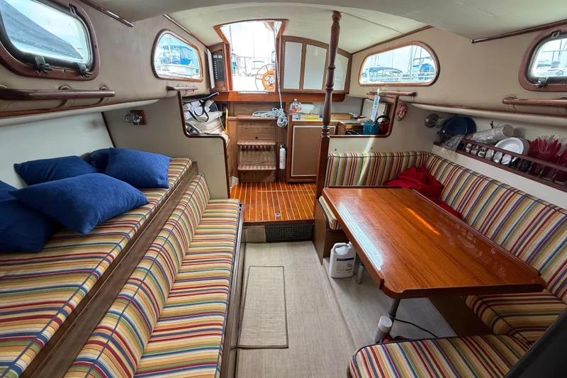 Slide: The Image of Cozy 1957 Rhodes Bounty boat interior with striped seating and wooden table. - 13