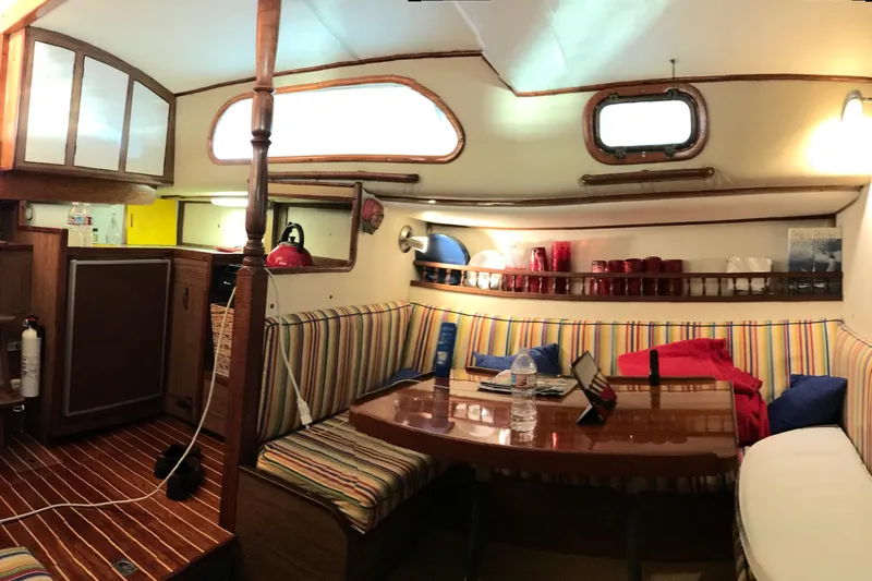 Slide: The Image of 1957 Rhodes Bounty yacht interior with striped seating, wooden table, and compact kitchen area. - 18