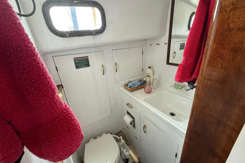 Slide: The Image of 1957 Rhodes Bounty boat bathroom with sink, mirror, and red towels. - 19