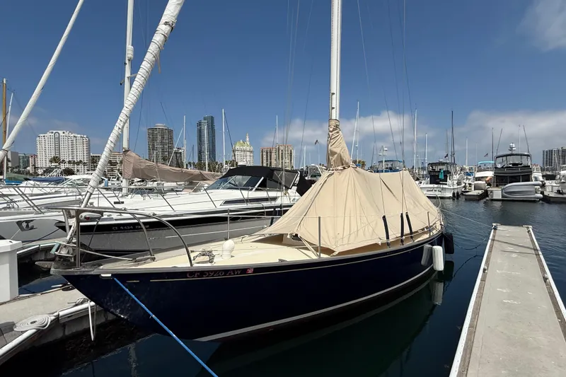 Slide: The Image of 1957 Rhodes Bounty sailboat docked in marina with city skyline background. - 22