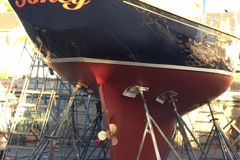 Slide: The Image of 1957 Rhodes Bounty sailboat on stands, showcasing its hull and propeller. - 23