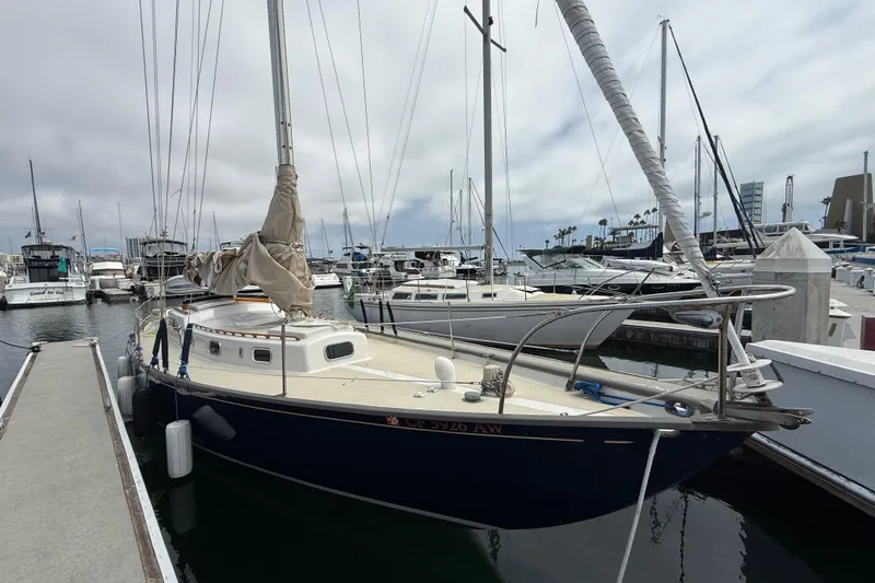 Slide: The Image of 1957 Rhodes Bounty sailboat docked at a marina, surrounded by other boats. - 3