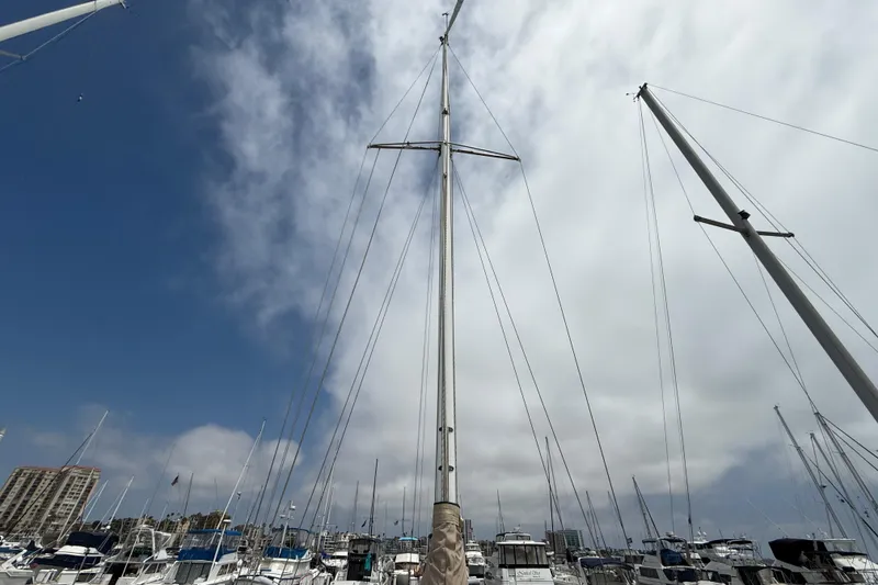 Slide: The Image of Sailboat masts against a cloudy sky, featuring a 1957 Rhodes Bounty model. - 7