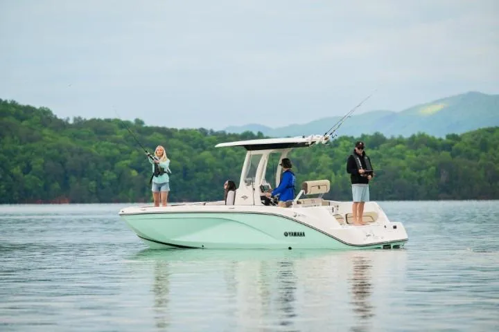 Slide: The Image of 2026 Yamaha Boats 222 FSH Sport E on a serene lake with people fishing. - 17