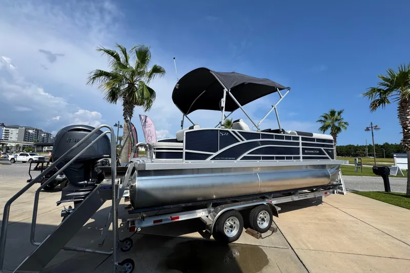 Slide: The Image of 2026 Bennington 22 SSB pontoon boat on trailer, parked near palm trees under a clear sky. - 11
