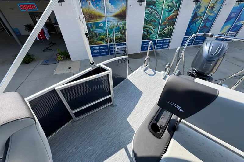 Slide: The Image of 2026 Bennington 22 SSB boat deck with seating and motor, near a mural-adorned building. - 32