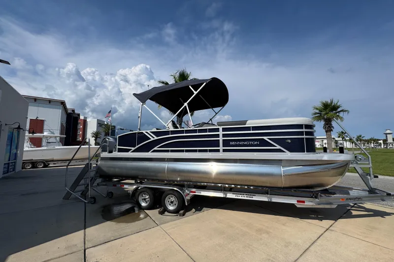 Slide: The Image of 2026 Bennington 22 SSB pontoon boat on trailer, parked outdoors under blue sky. - 9