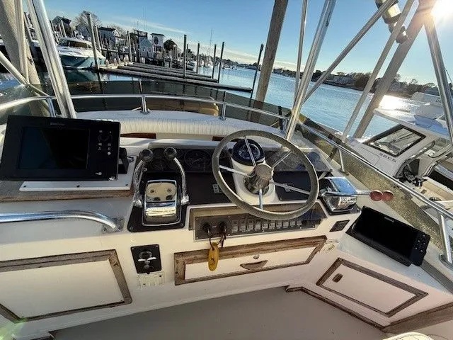 Slide: The Image of 1988 Blackfin 32 Flybridge helm with steering wheel, controls, and navigation equipment at marina. - 12