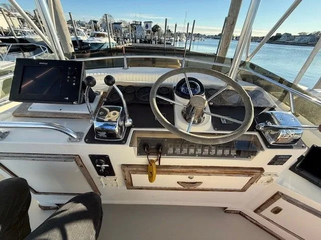 Slide: The Image of 1988 Blackfin 32 Flybridge helm with steering wheel, controls, and navigation equipment, docked at marina. - 15