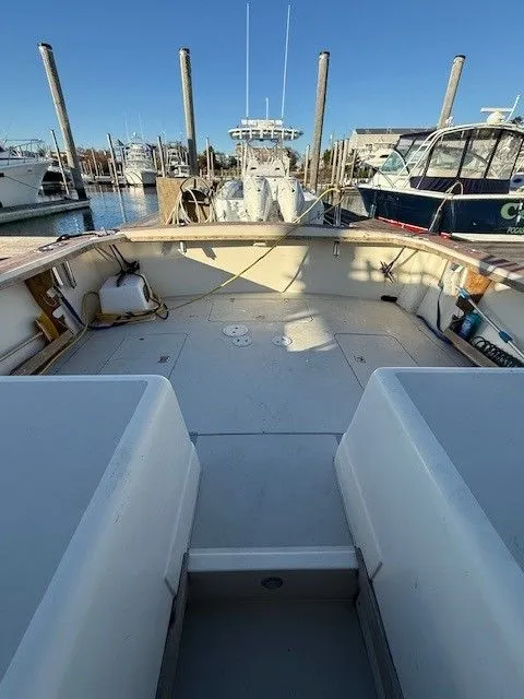 Slide: The Image of 1988 Blackfin 32 Flybridge boat docked at marina, spacious deck, clear blue sky. - 16