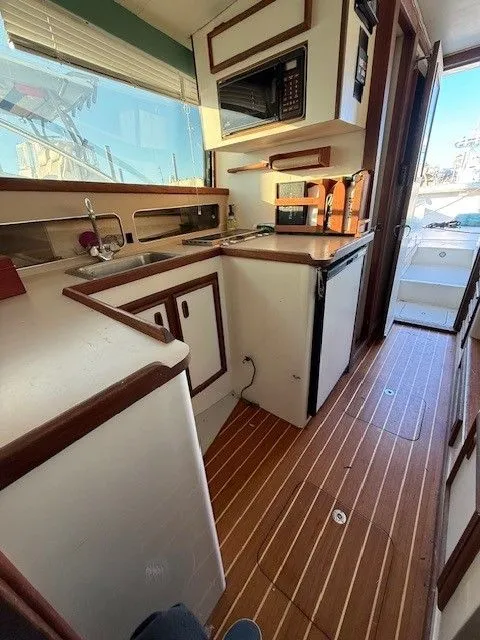 Slide: The Image of 1988 Blackfin 32 Flybridge interior with kitchenette, featuring wood flooring and modern appliances. - 23