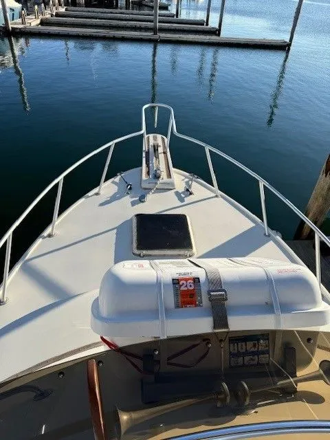 Slide: The Image of 1988 Blackfin 32 Flybridge boat bow view at marina, featuring life raft and calm waters. - 9