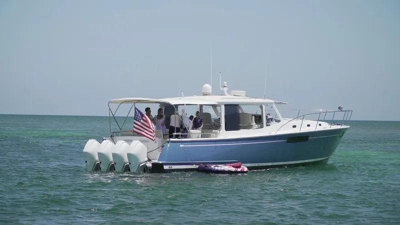 Slide: The Image of 2021 MJM 53z boat on water with American flag, featuring multiple outboard engines. - 5