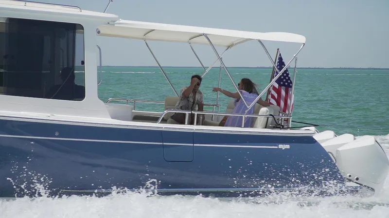 Slide: The Image of 2021 MJM 53z boat cruising with passengers, American flag, and ocean backdrop. - 8