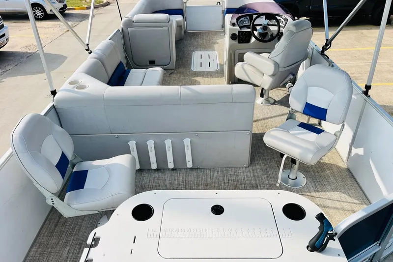 Slide: The Image of 2019 SunCatcher V322 RF boat interior with gray and blue seating, cup holder, and textured flooring. - 11