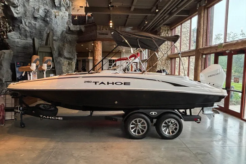 Slide: The Image of 2025 Tahoe 2150 boat displayed indoors on a trailer. - 0