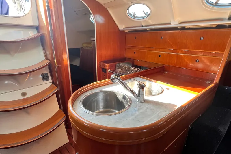 Slide: The Image of Interior of 1994 Beneteau First 35s7 yacht, featuring a wooden galley with sink and storage. - 33