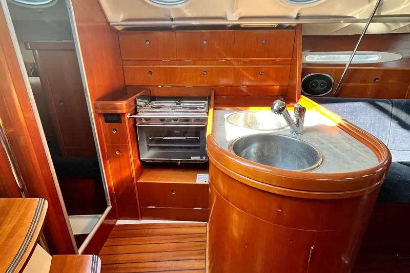 Slide: The Image of Interior of 1994 Beneteau First 35s7 yacht with wooden cabinetry and compact kitchen area. - 34