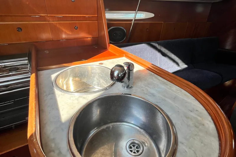 Slide: The Image of Interior of 1994 Beneteau First 35s7 yacht, featuring a dual sink and wooden cabinetry. - 35