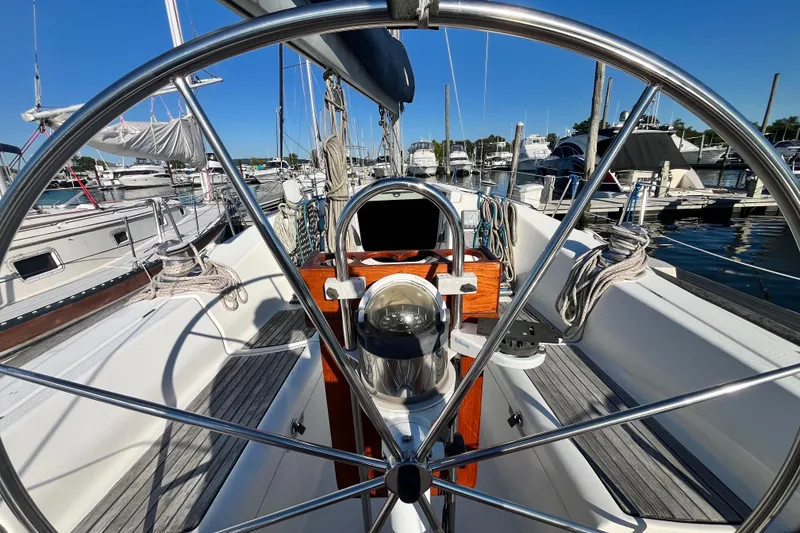 Slide: The Image of Cockpit view of 1994 Beneteau First 35s7 sailboat, featuring steering wheel and marina backdrop. - 7