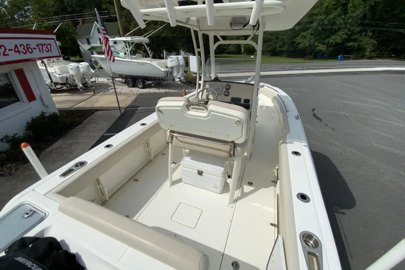 Slide: The Image of 2019 Boston Whaler 230 Outrage boat interior with seating and console, parked outdoors. - 9