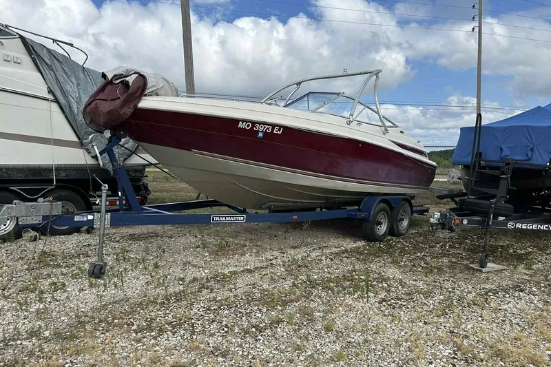 Slide: The Image of 1997 Maxum 2300 SR boat on trailer, parked outdoors under cloudy sky. - 0