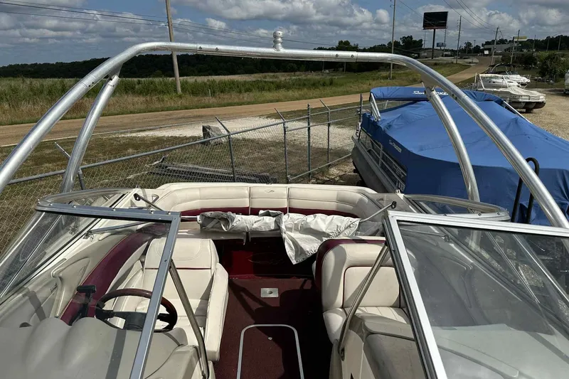 Slide: The Image of 1997 Maxum 2300 SR boat with open cockpit and seating, parked near a fence. - 21
