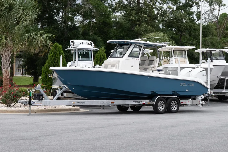 The Image of 2026 Solace 28 HCS boat on trailer, parked outdoors with trees in background. - 1
