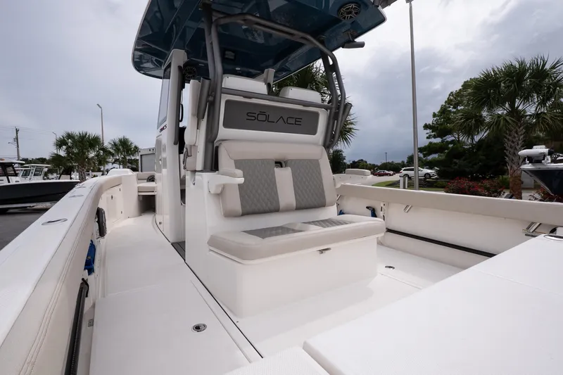 Slide: The Image of 2026 Solace 28 HCS boat interior with seating, sleek design, and palm trees in the background. - 13
