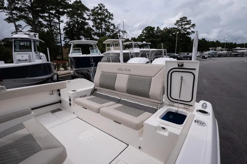 Slide: The Image of 2026 Solace 28 HCS boat interior with seating and storage, parked outdoors. - 16