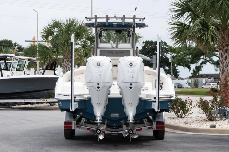Slide: The Image of 2026 Solace 28 HCS boat with dual engines on trailer, surrounded by palm trees. - 6