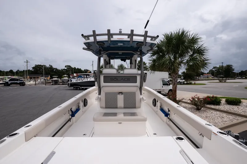 Slide: The Image of 2026 Solace 28 HCS boat interior with seating and helm, parked outdoors. - 9