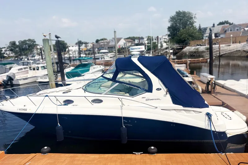 The Image of 2006 Sea Ray 320 Sundancer docked at a marina, featuring a sleek design and blue canopy. - 0
