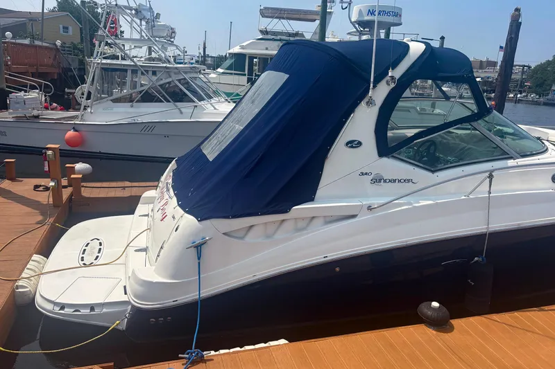 Slide: The Image of 2006 Sea Ray 320 Sundancer docked, featuring a blue canopy and sleek design. - 2