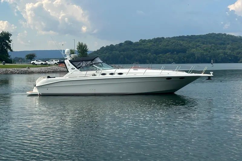 Slide: The Image of 1997 Sea Ray 400 Express Cruiser on a serene lake with lush green hills. - 1
