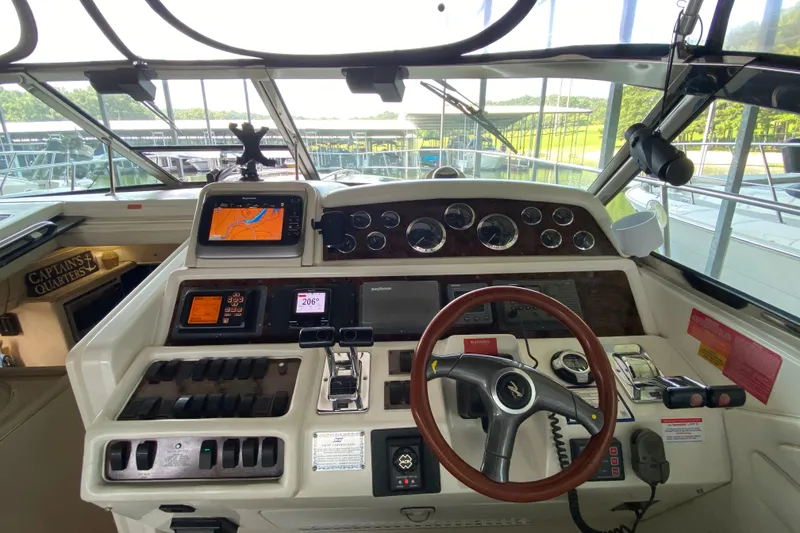 Slide: The Image of 1997 Sea Ray 400 Express Cruiser helm with navigation instruments and steering wheel. - 10