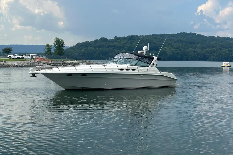 Slide: The Image of 1997 Sea Ray 400 Express Cruiser on a serene lake with wooded hills in the background. - 2
