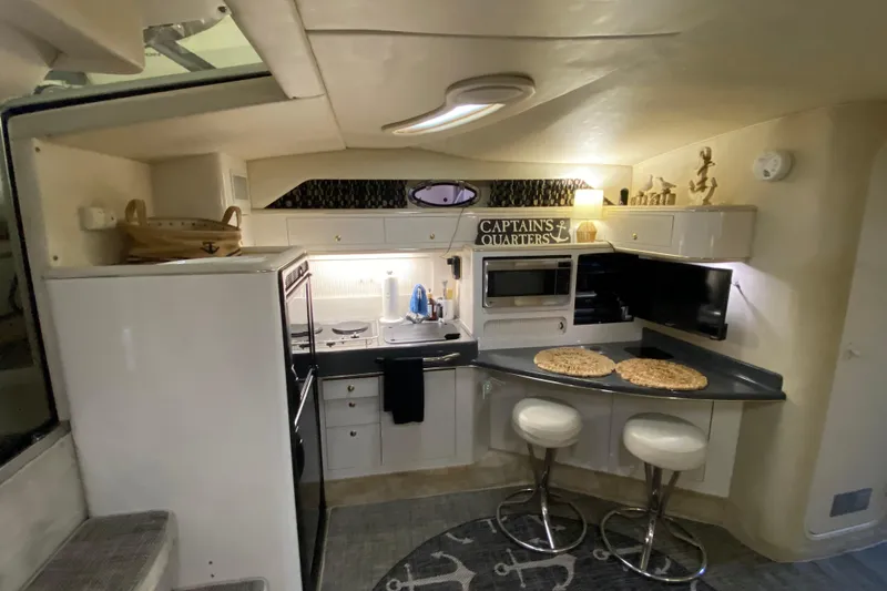 Slide: The Image of Interior of 1997 Sea Ray 400 Express Cruiser with modern kitchen and bar stools. - 27